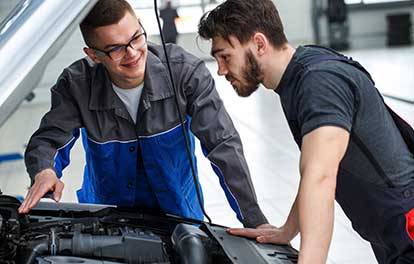 Young men inspecting automobile engine