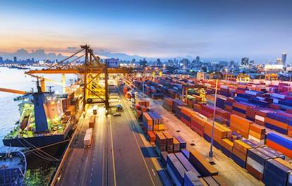 Busy port scene with ship and many containers being loaded